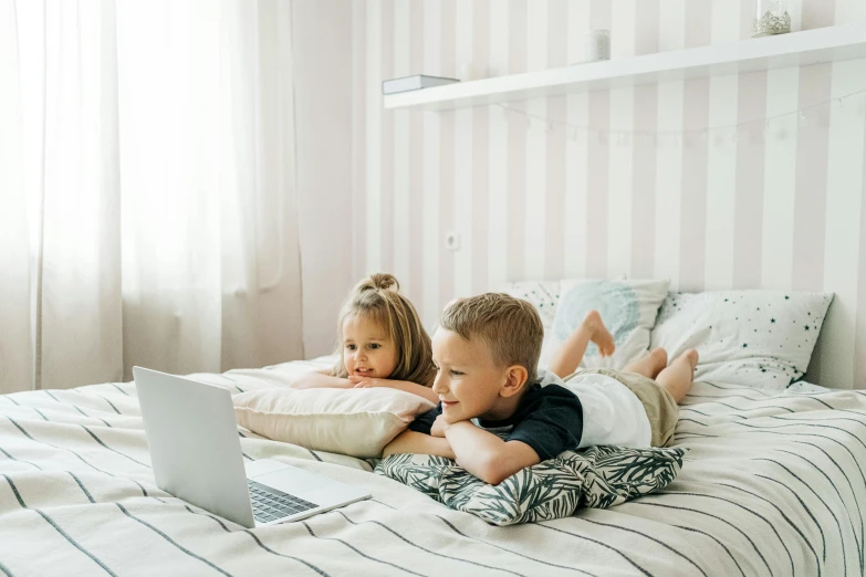 a couple of kids laying on a bed with a laptop, pexels contest winner, tv series, 000 — википедия, small bedroom, instagram post