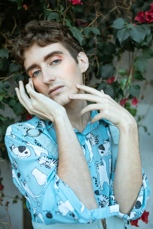 a man in a blue shirt posing for a picture, an album cover, by Jessie Alexandra Dick, trending on pexels, aestheticism, non binary model, patterned clothing, hands on face, adam ondra