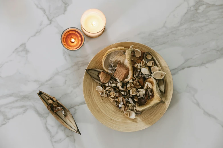 a close up of a bowl of food on a table, a still life, trending on pexels, natural candle lighting, shells, wooden decoration, set against a white background