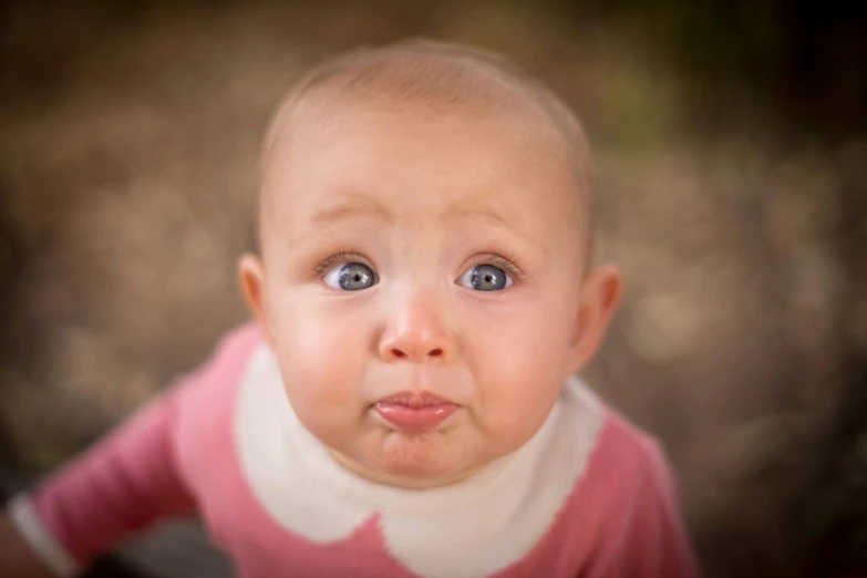 a close up of a baby looking at the camera, by Lee Loughridge, pexels contest winner, confused facial expression, pink, professionally post - processed, shrugging