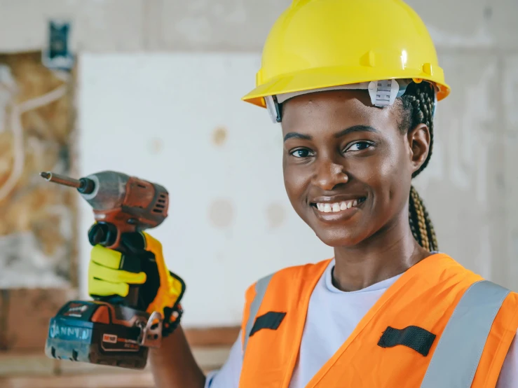 a woman in a hard hat holding a drillet, inspired by Afewerk Tekle, pexels contest winner, cheerful, african sybil, saws, instagram post