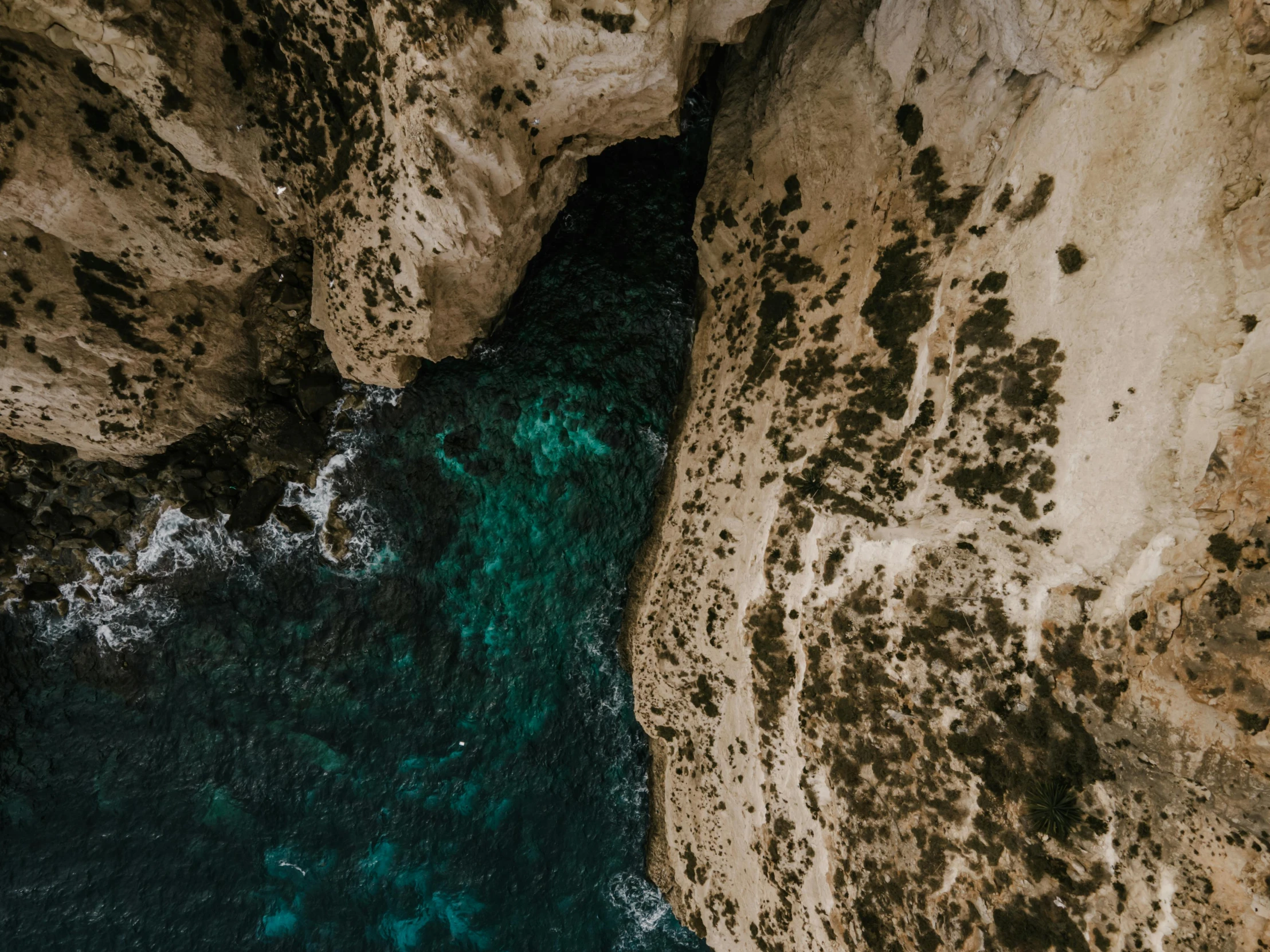 a man standing on top of a cliff next to the ocean, pexels contest winner, les nabis, natural cave wall, close-up from above, limestone, teal aesthetic