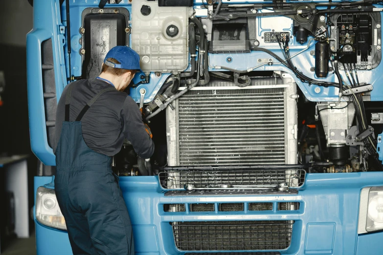 a man working on a blue truck in a garage, shutterstock, engine, avatar image, robot made of truck parts, fan favorite