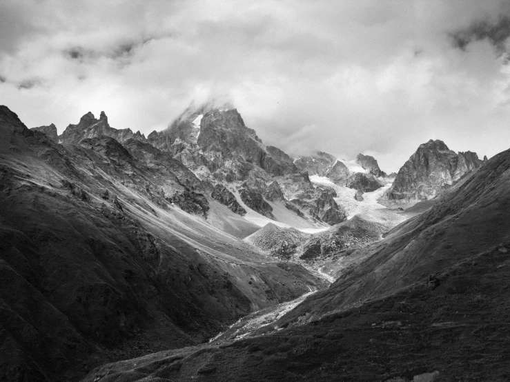 a black and white photo of a mountain range, by Cedric Peyravernay, unsplash contest winner, in a valley, complex and desaturated, larapi, glacier