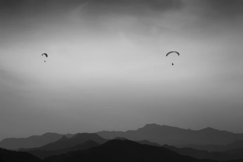 a black and white photo of two paragliders in the sky, by Jan Kupecký, pexels contest winner, minimalism, zezhou chen, hills, photographic print, wallpaper mobile