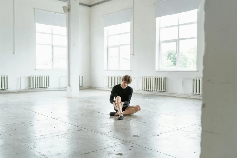 a woman sitting on the floor in an empty room, by Nina Hamnett, unsplash, alexey egorov, choreographed, ignant, 'untitled 9 '