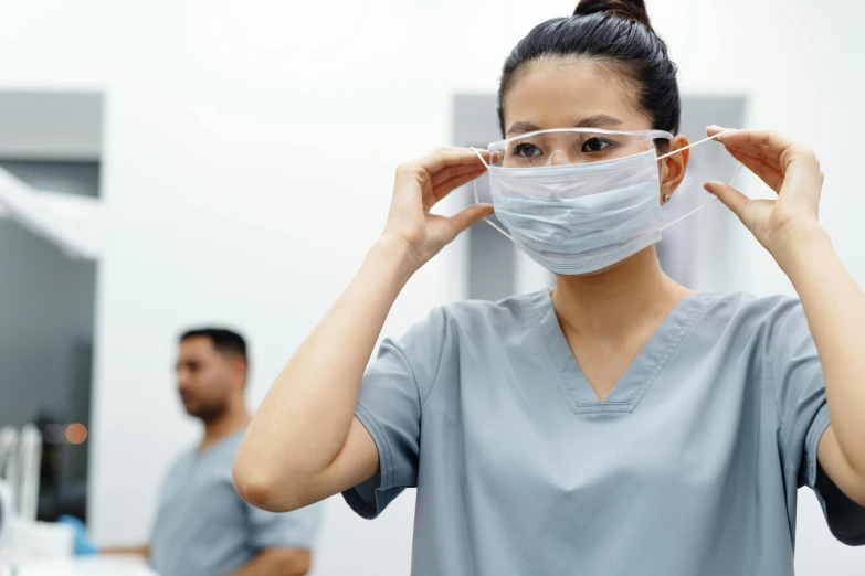a woman with a surgical mask covering her face, a picture, shutterstock, hurufiyya, nurse uniform, lined up horizontally, wearing round glasses, grey