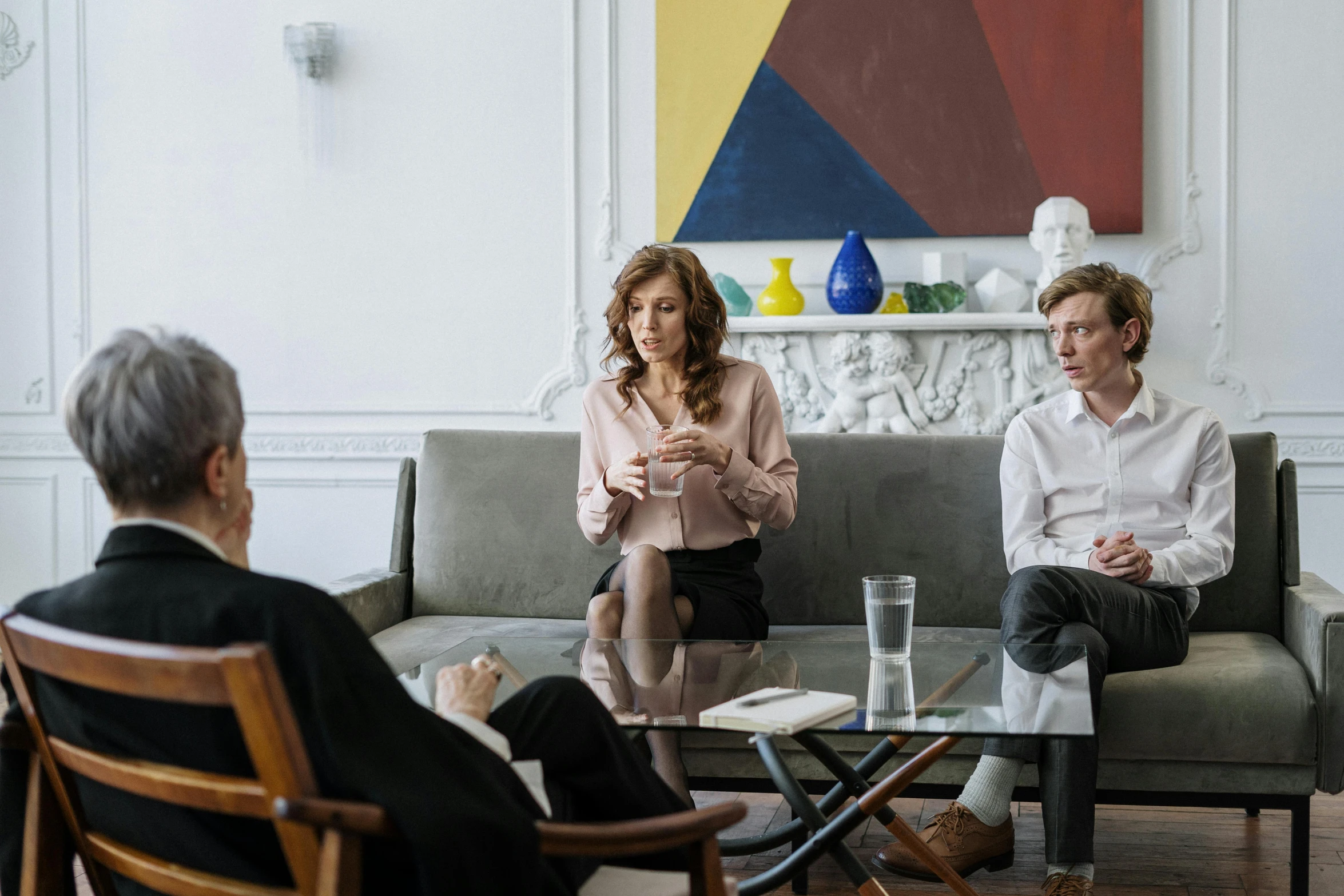 a group of people sitting on a couch in a living room, by Sebastian Vrancx, pexels, figuration libre, seated in court, serious business, husband wife and son, on a white table