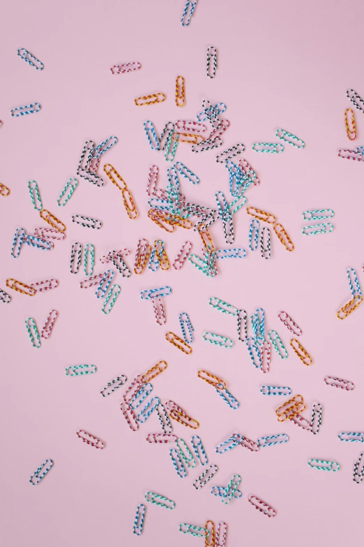 a bunch of confetti sprinkles on a pink surface, by Rachel Reckitt, made of paperclips, swarovski crystals, repeating pattern, dimmed pastel colours
