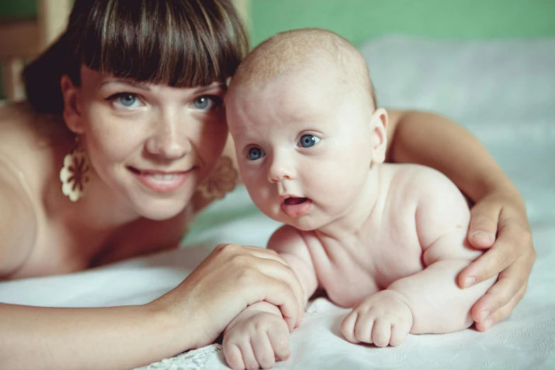 a woman laying on a bed holding a baby, by Julia Pishtar, shutterstock, lovingly looking at camera, avatar image, 2263539546], ukrainian