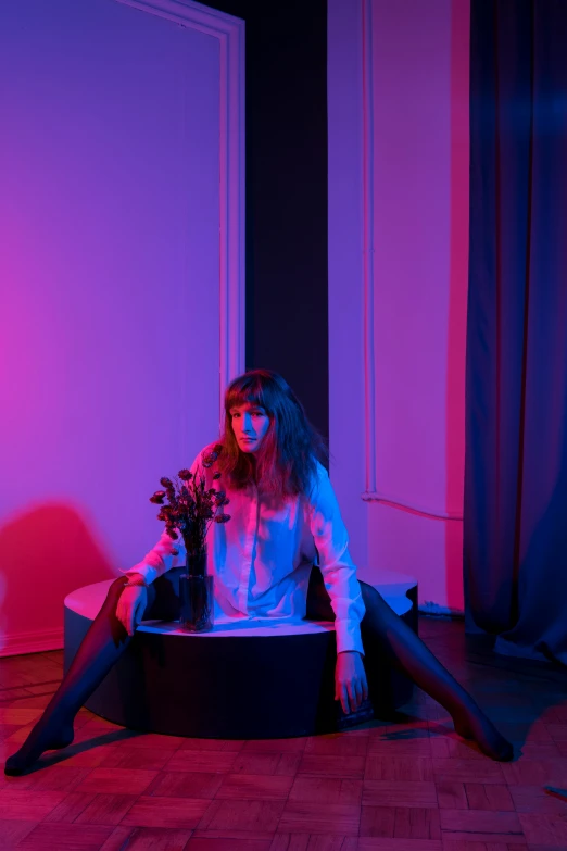 a woman sitting on a couch in a room, an album cover, inspired by Elsa Bleda, with bangs, violet lighting, marat zakirov, concert photo