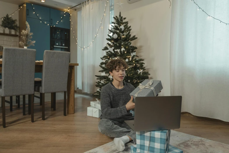 a person sitting on the floor with a laptop, christmas tree, for junior, artem chebokha, presents
