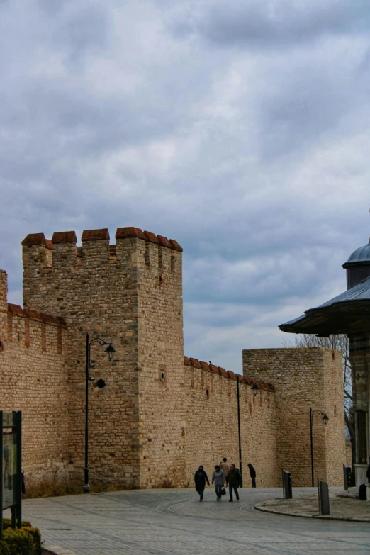 a group of people walking in front of a castle, brick walls, byzantine, tall metal towers, panorama shot