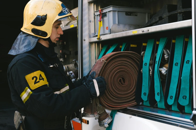 a firefighter putting a fire hose into the back of a fire truck, a photo, arbeitsrat für kunst, jovana rikalo, brown, 3 4 5 3 1, branding