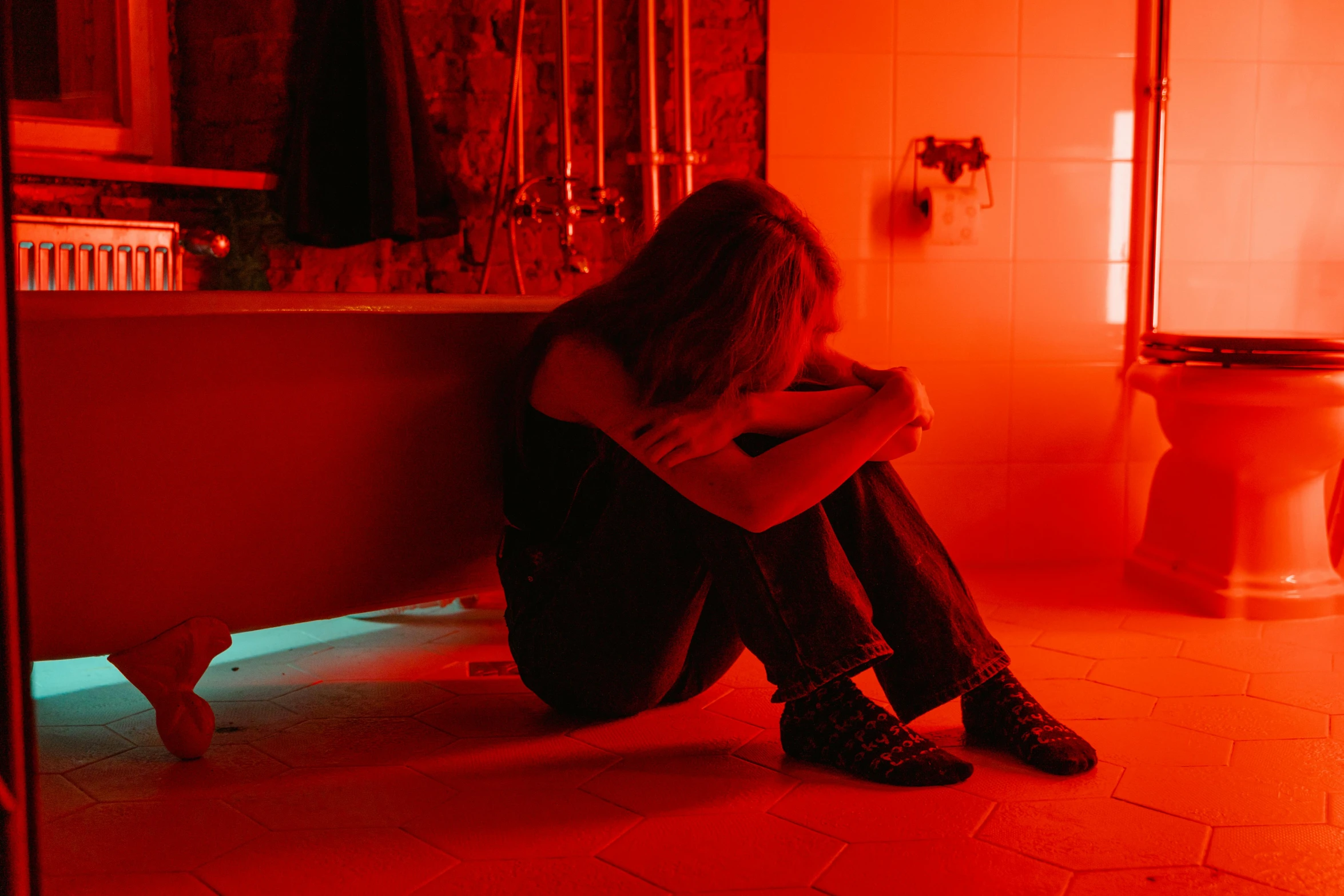 a woman sitting in a bathtub in a bathroom, inspired by Nan Goldin, pexels, red neon, upset, teenage, sitting on a bed