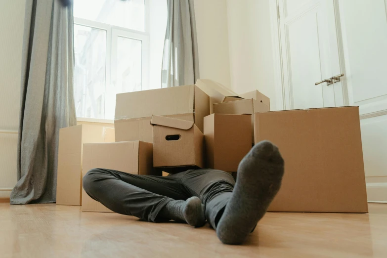 a man laying on the floor surrounded by boxes, a cartoon, by Carey Morris, pexels contest winner, hurufiyya, melbourne, leaving a room, pants, [ forgetful ]