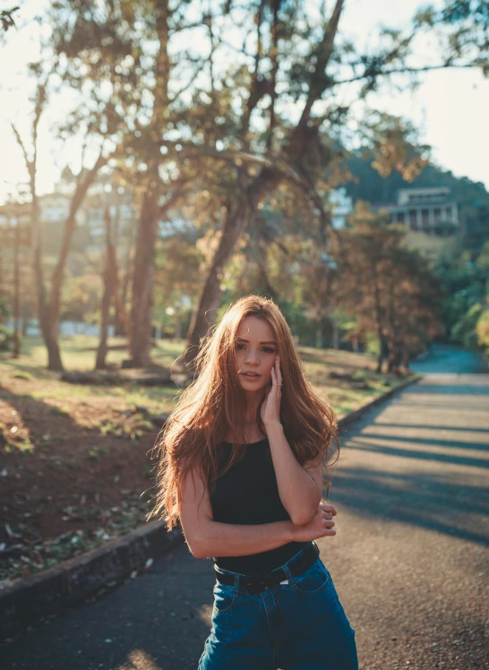 a woman standing on the side of a road talking on a cell phone, inspired by Elsa Bleda, unsplash contest winner, renaissance, thin long auburn hair, sunny day in a park, panoramic view of girl, 🤤 girl portrait