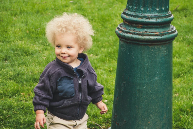 a little boy standing next to a green pole, inspired by Myles Birket Foster, pexels contest winner, short blonde afro, 2 years old, urban surroundings, high resolution details