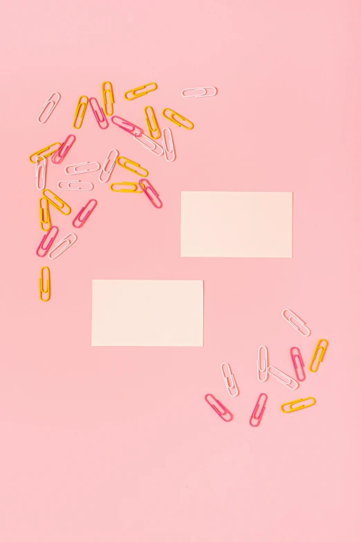 a bunch of paper clips sitting on top of a pink surface, by Nicolette Macnamara, pills, ffffound, labels, background image