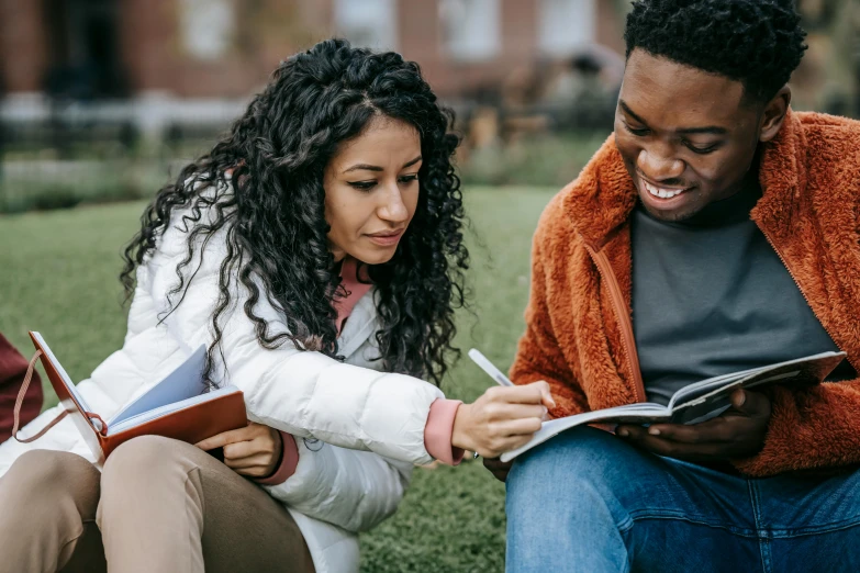 a couple of people sitting on top of a grass covered field, trending on pexels, academic art, holding notebook, mixed race, 1 4 9 3, thumbnail