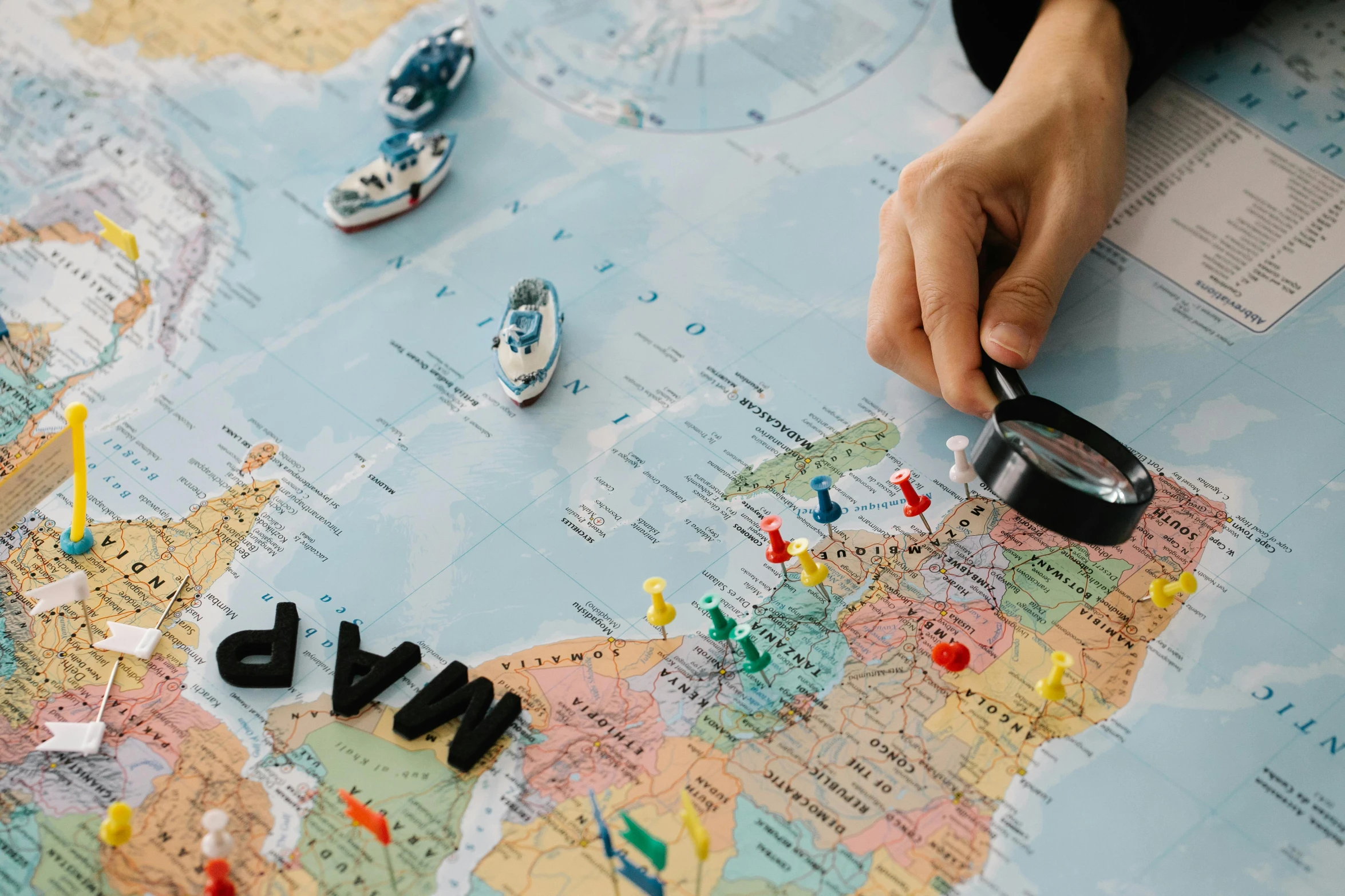 a person holding a magnifying glass over a map, a jigsaw puzzle, by Daniel Lieske, pexels contest winner, warships, 🚿🗝📝, board games on a table, amanda clarke