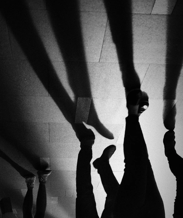 a black and white photo of a group of people doing handstands, by Mirko Rački, unsplash, conceptual art, lights and shadows, feet and hands, instagram photo, shadow gradient