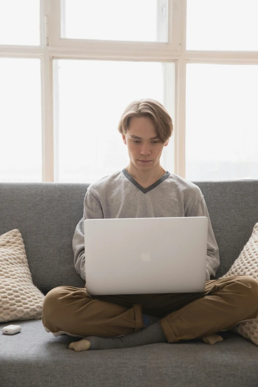 a person sitting on a couch with a laptop, pexels, boy with neutral face, overcast, androgynous male, white male