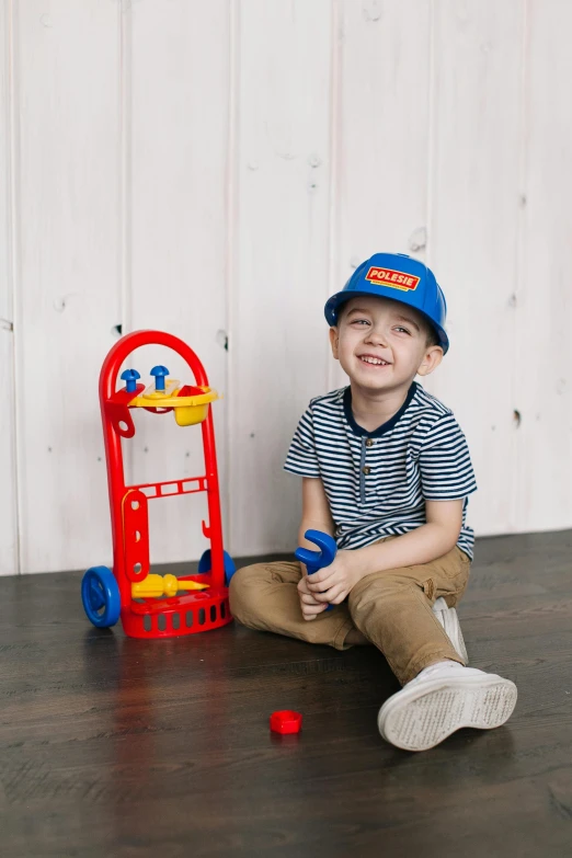 a little boy that is sitting on the floor, blippi, hand holding cap brim, cart, professionally assembled