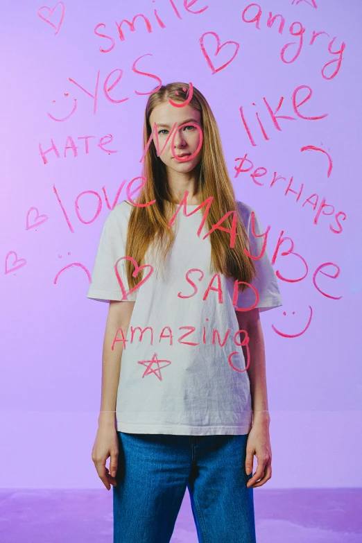 a woman standing in front of a wall with writing on it, an album cover, by Sara Saftleven, trending on pexels, antipodeans, sadie sink, love hate love, colorized, grimacing