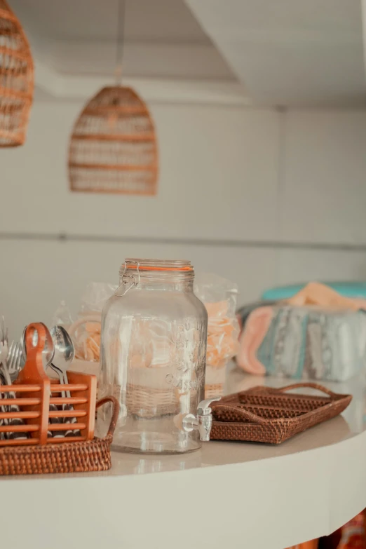 a table with a glass jar on top of it, orange pastel colors, wicker art, shot on sony a 7 iii, store