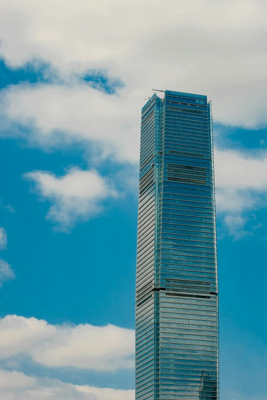 a tall building sitting on top of a lush green field, in hong kong, trump tower, blue skies, award-winning”