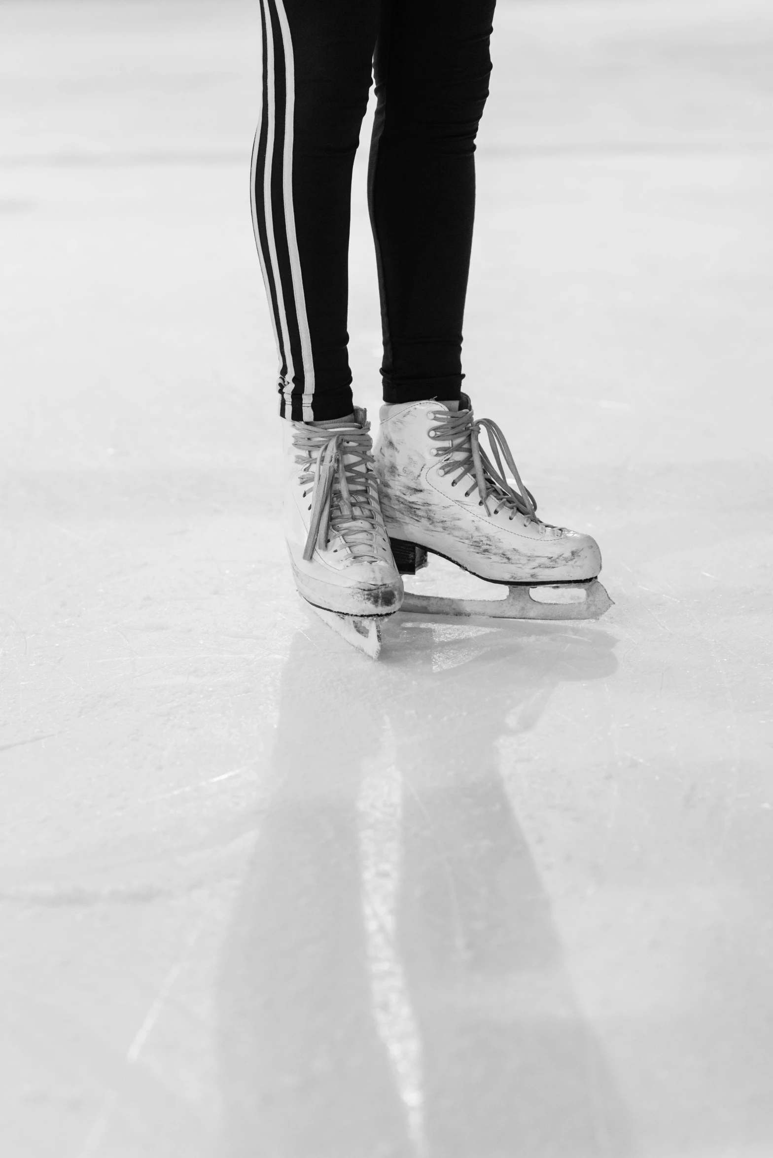 a black and white photo of a person on a skateboard, by Maggie Hamilton, pexels contest winner, walking on ice, leotard and leg warmers, shiny silver, standing in an arena