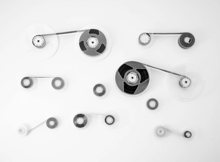 a clock sitting on top of a white table, a black and white photo, inspired by László Moholy-Nagy, unsplash, kinetic art, screws, floating headsets, various sizes, stainless steel