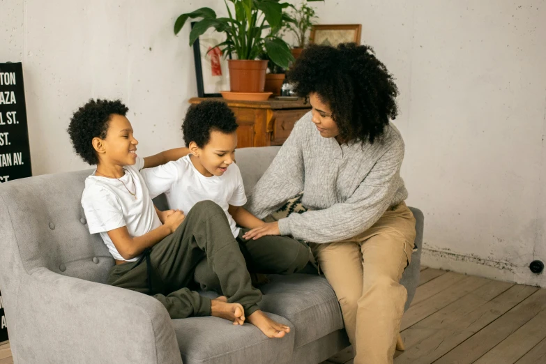 a woman and two children sitting on a couch, pexels, african american, maintenance, comfy chairs, grey