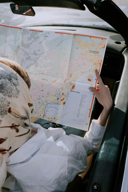 a person sitting in a car looking at a map, wearing lab coat and a blouse, wearing a head scarf, flatlay, 2019 trending photo