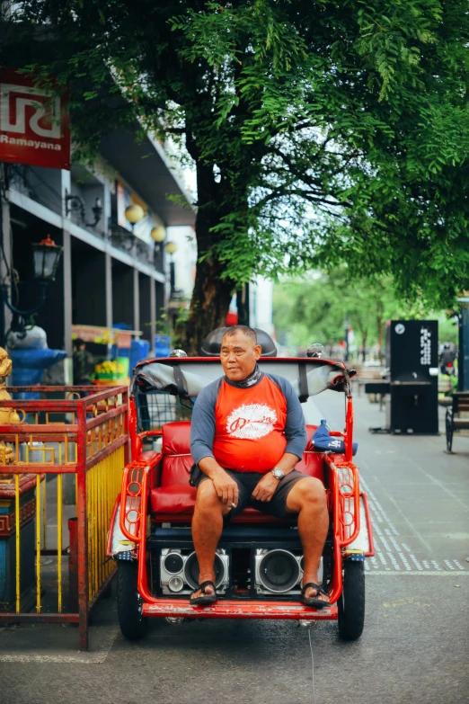 a man riding on the back of a red vehicle, by Yosa Buson, pexels contest winner, bangkok townsquare, sitting in a wheelchair, gif, lush surroundings