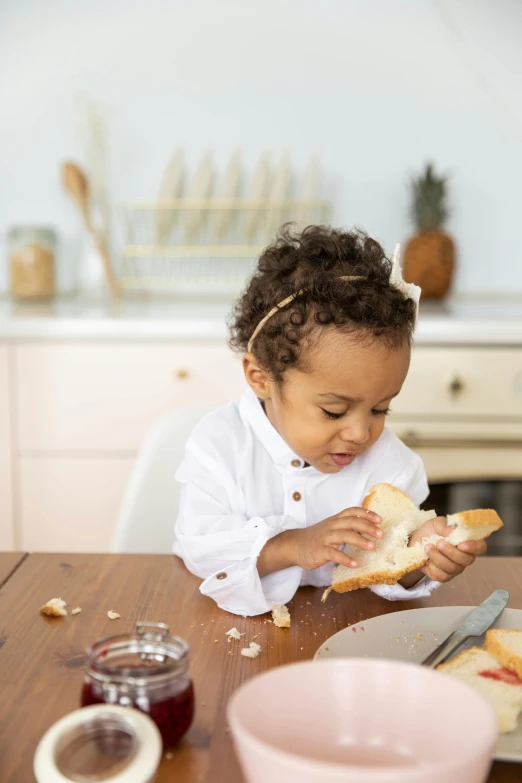 a little girl sitting at a table eating a sandwich, by Nicolette Macnamara, baking french baguette, press shot, vanilla, toddler