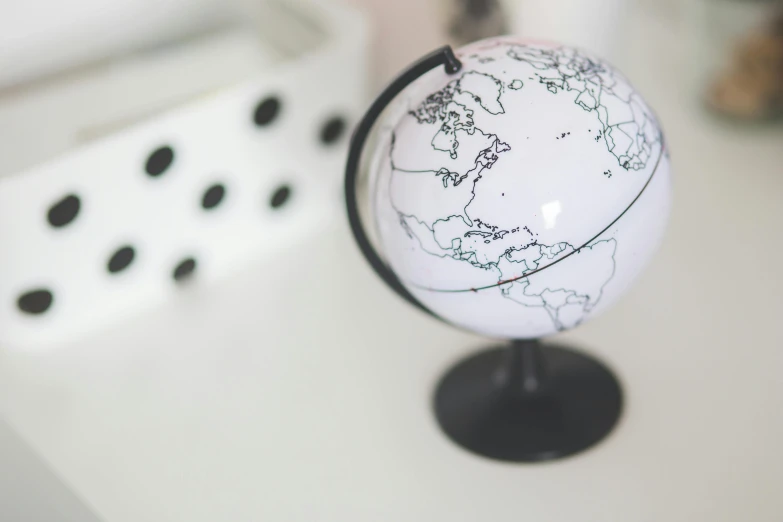 a white and black globe sitting on top of a table, by Arabella Rankin, trending on unsplash, polka dot, world map, white plastic, well drawn