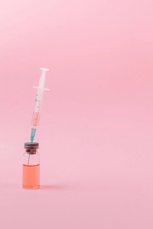 a syll sitting on top of a pink surface, pexels, holding syringe, on a pale background, close together, bottle