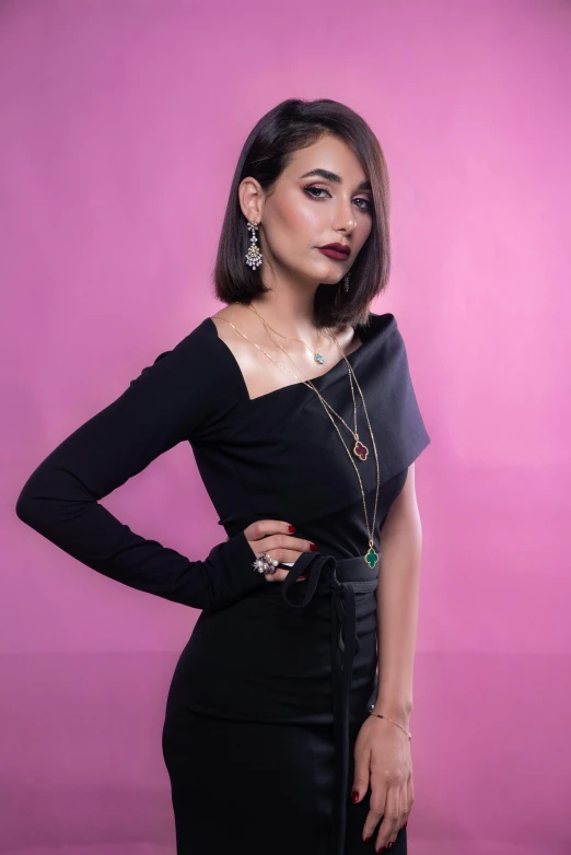 a woman in a black dress posing for a picture, an album cover, inspired by Niyazi Selimoglu, trending on instagram, cyber necklace, taken with sony alpha 9, plain background, middle eastern