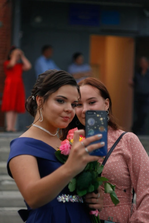 a couple of women standing next to each other, a picture, reddit, happening, wearing a formal dress, cell phone photo, bouquet, student