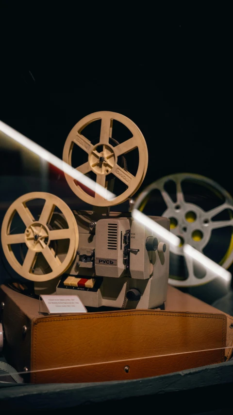 a projector sitting on top of a wooden table, by Everett Warner, trending on pexels, video art, old retro museum exhibition, 1960s color photograph, celluloid, brown