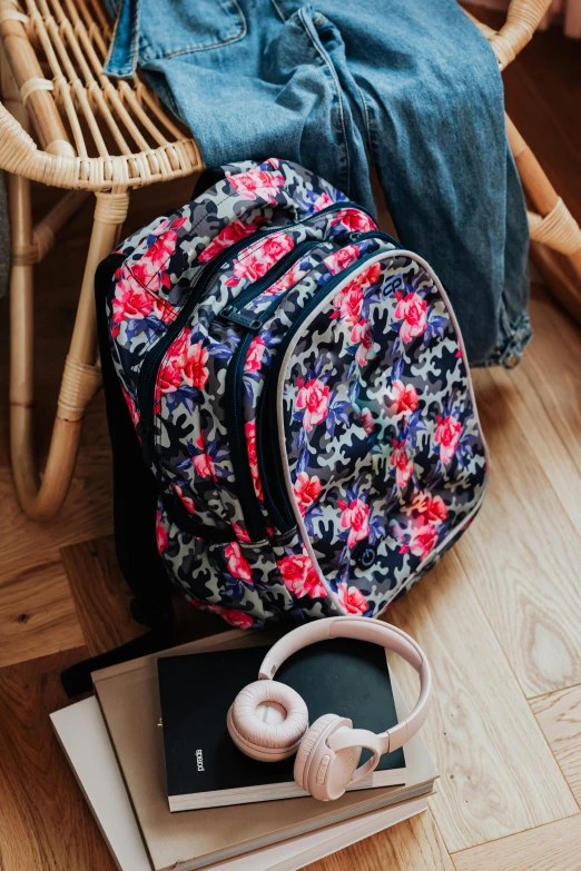 a backpack sitting on top of a wooden floor next to a stack of books, by Julia Pishtar, neon floral pattern, school uniform, productphoto, rubens