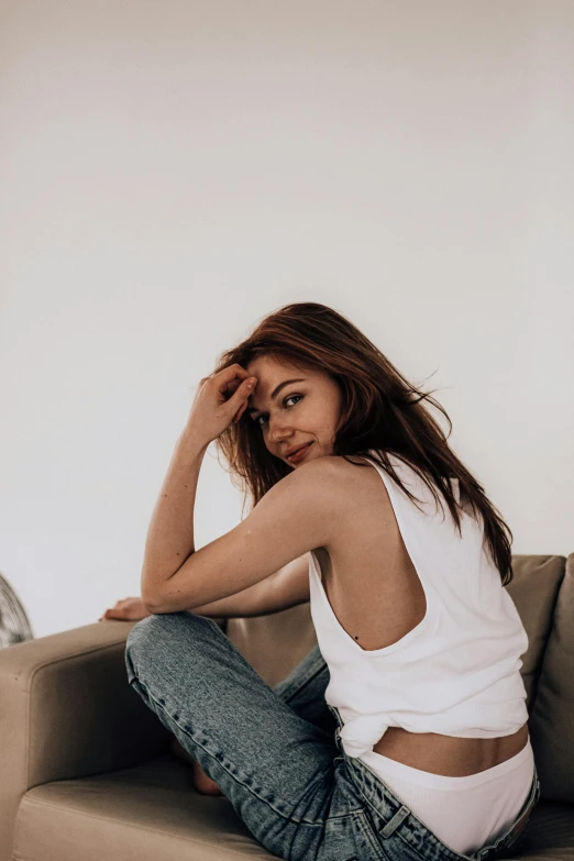 a beautiful young woman sitting on top of a couch, inspired by Natasha Tan, trending on pexels, happening, dressed in a white t shirt, zendaya, wearing tank top, promotional image