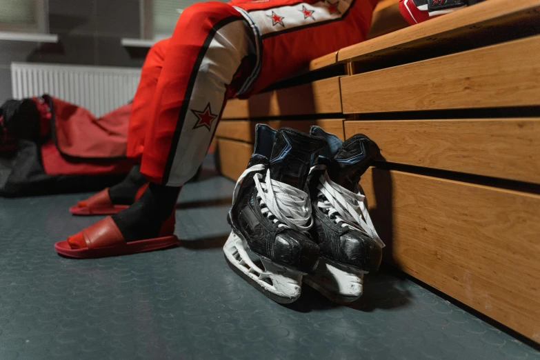 a person sitting on a bench next to a pair of hockey shoes, by Adam Marczyński, pexels contest winner, photorealism, locker room, devils, shooting stars, cel shaded pbr