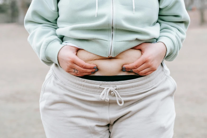 a close up of a person holding their stomach, by Julia Pishtar, trending on pexels, plus-sized, wearing pants, thick outlines, katey truhn