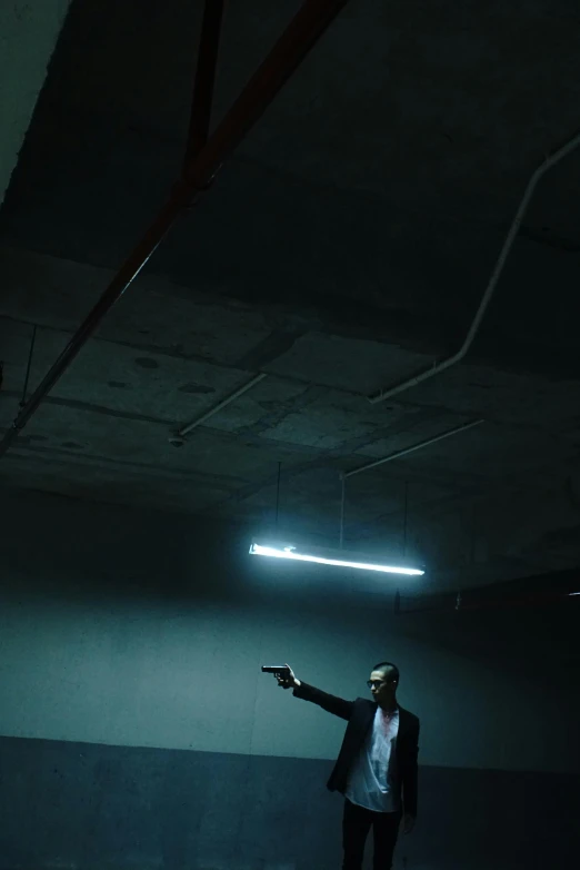 a man in a suit standing in a dark room, an album cover, unsplash, gun fight, set inside of parking garage, ( ( theatrical ) ), lights on ceiling