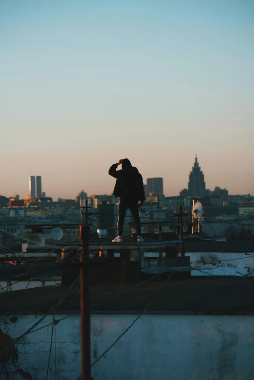 a man standing on top of a roof next to a body of water, an album cover, by Attila Meszlenyi, pexels contest winner, happening, russian city, silhouettes, 15081959 21121991 01012000 4k