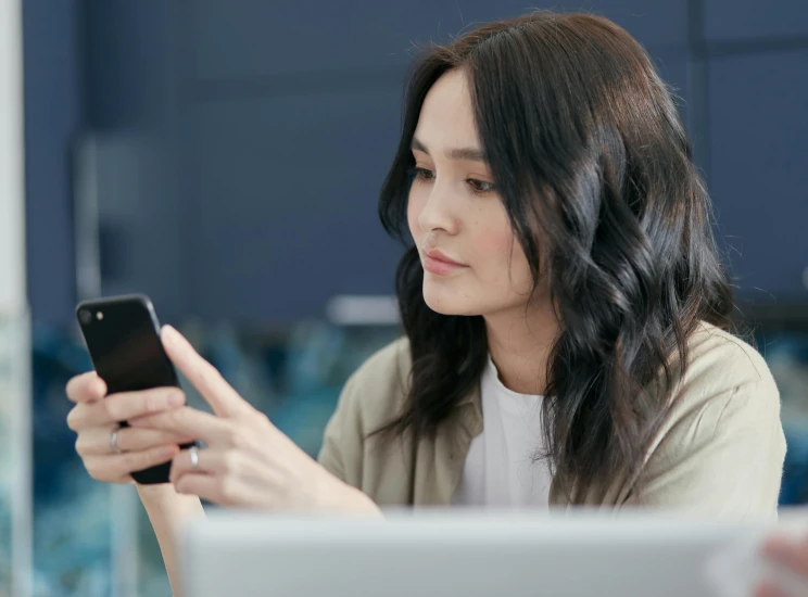 a woman sitting at a table looking at her cell phone, trending on pexels, female with long black hair, avatar image, looking at monitor, rounded corners