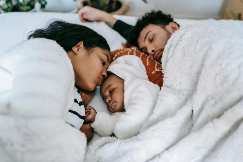 a man and woman laying in bed with a baby, pexels contest winner, symbolism, varying ethnicities, asleep, profile image, husband wife and son